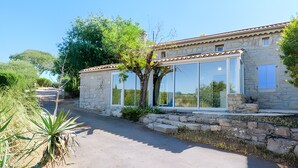 A stone building with large windows and a tree in front.
