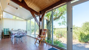 A spacious patio with a dining area, large windows, and a view of the outdoors.