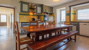 Een keuken met een houten tafel en stoelen, een inbouwoven en een vaatwasser.