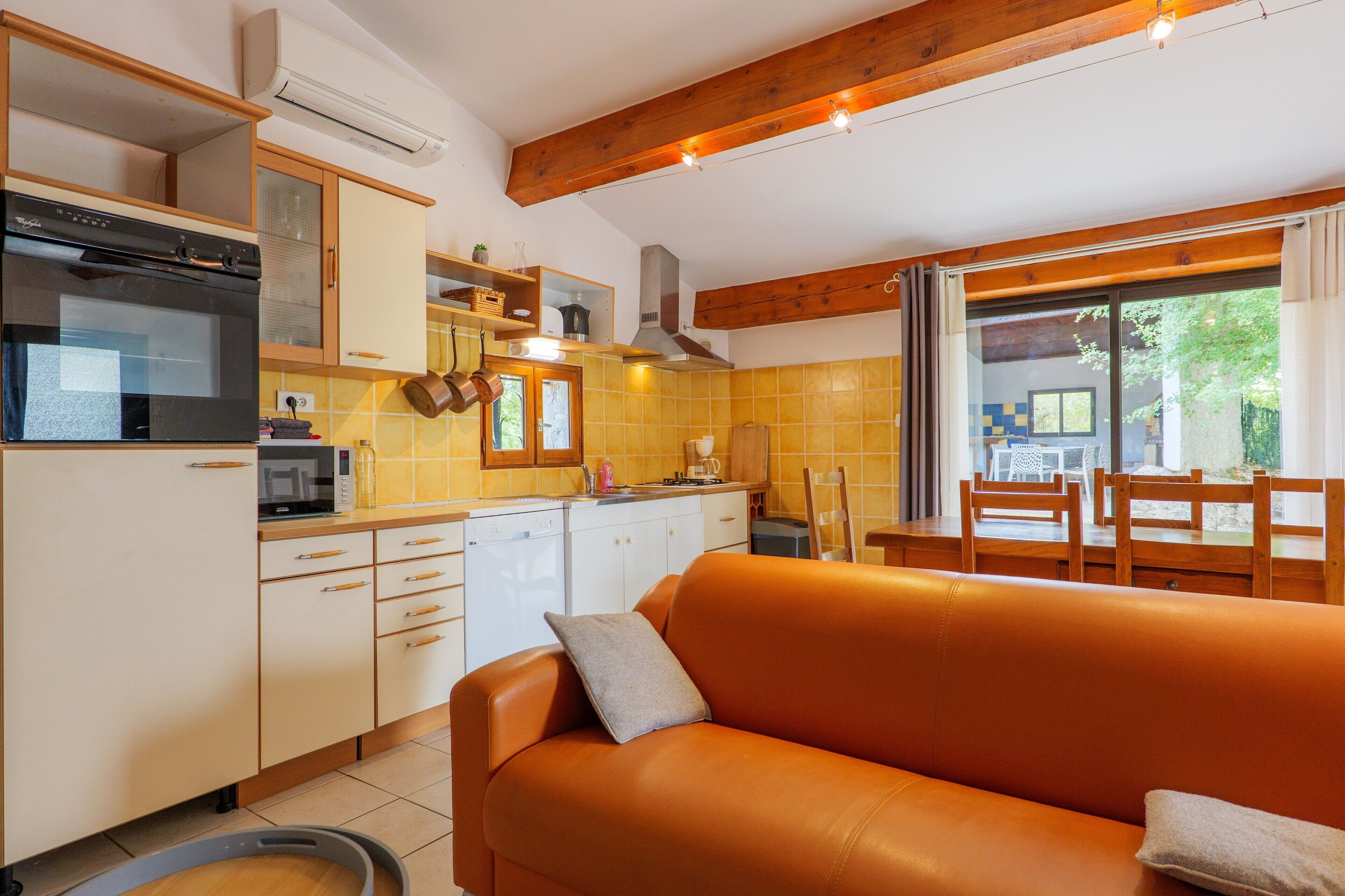 A kitchen with a built-in oven, microwave, and sink. There is a dining area with a wooden table and chairs.