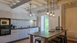 Een moderne keuken met witte kasten, een centraal eiland met krukken, hangende吊灯 en uitzicht op de omgeving.