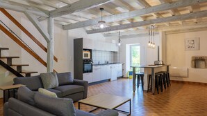 Een ruime woonkamer met een bank, salontafel en een keuken op de achtergrond.