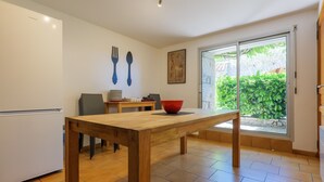 A kitchen with a wooden table, a red bowl, a white refrigerator, and a dining area with chairs.