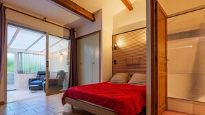A bedroom with a bed, sliding glass doors leading to a patio, and a wooden ceiling.