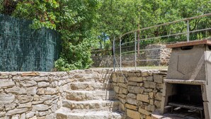 Un escalier en pierre menant à un mur de pierre, une clôture en métal et un espace barbecue.