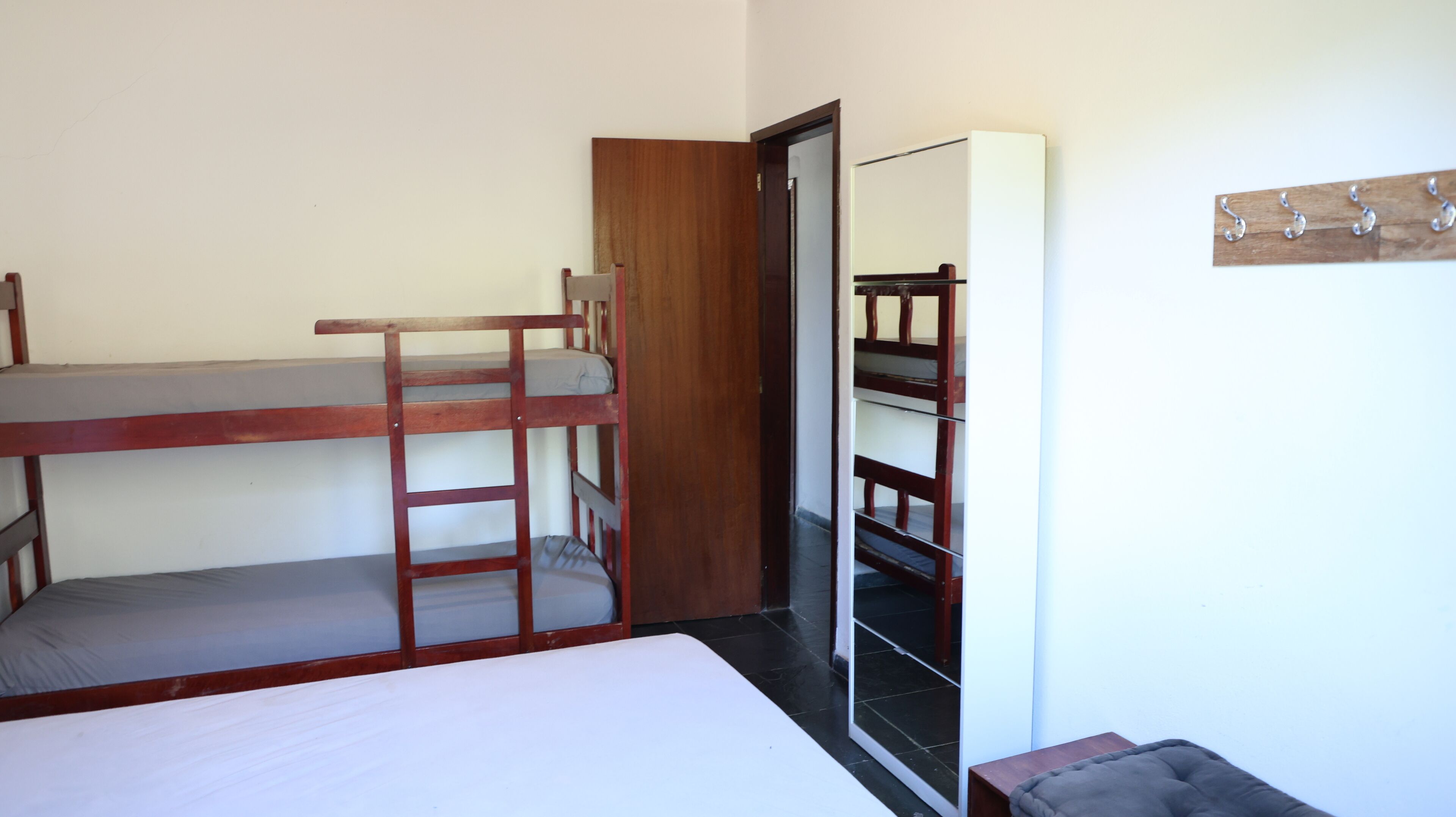 A bunk bed room with a wooden ladder, a wardrobe, and a mirror.