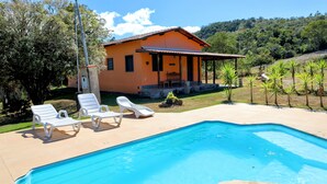 Une piscine entourée de chaises longues, avec une maison en arrière-plan.
