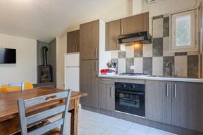 Une cuisine moderne avec des meubles en bois, un four encastré et un téléviseur à écran plat fixé au mur.