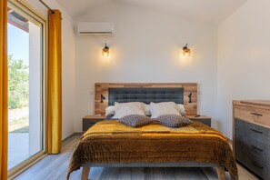 Un dormitorio con una cama, mesitas de noche, cabecero de madera y dos lámparas fijadas a la pared.