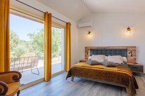 Un dormitorio con cama, mesita de noche, silla y vistas al exterior.