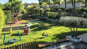 Un jardin bien entretenu, équipé d’une balançoire, d’un espace de jeux et de bancs.