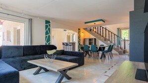 Un salon moderne avec un canapé d’angle, une table basse en bois et un escalier menant à l’étage supérieur.
