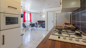 Una cocina con estufa, horno y un comedor con sillas y mesa.