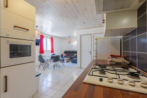A kitchen with a stove, oven, and a dining area with chairs and a table.