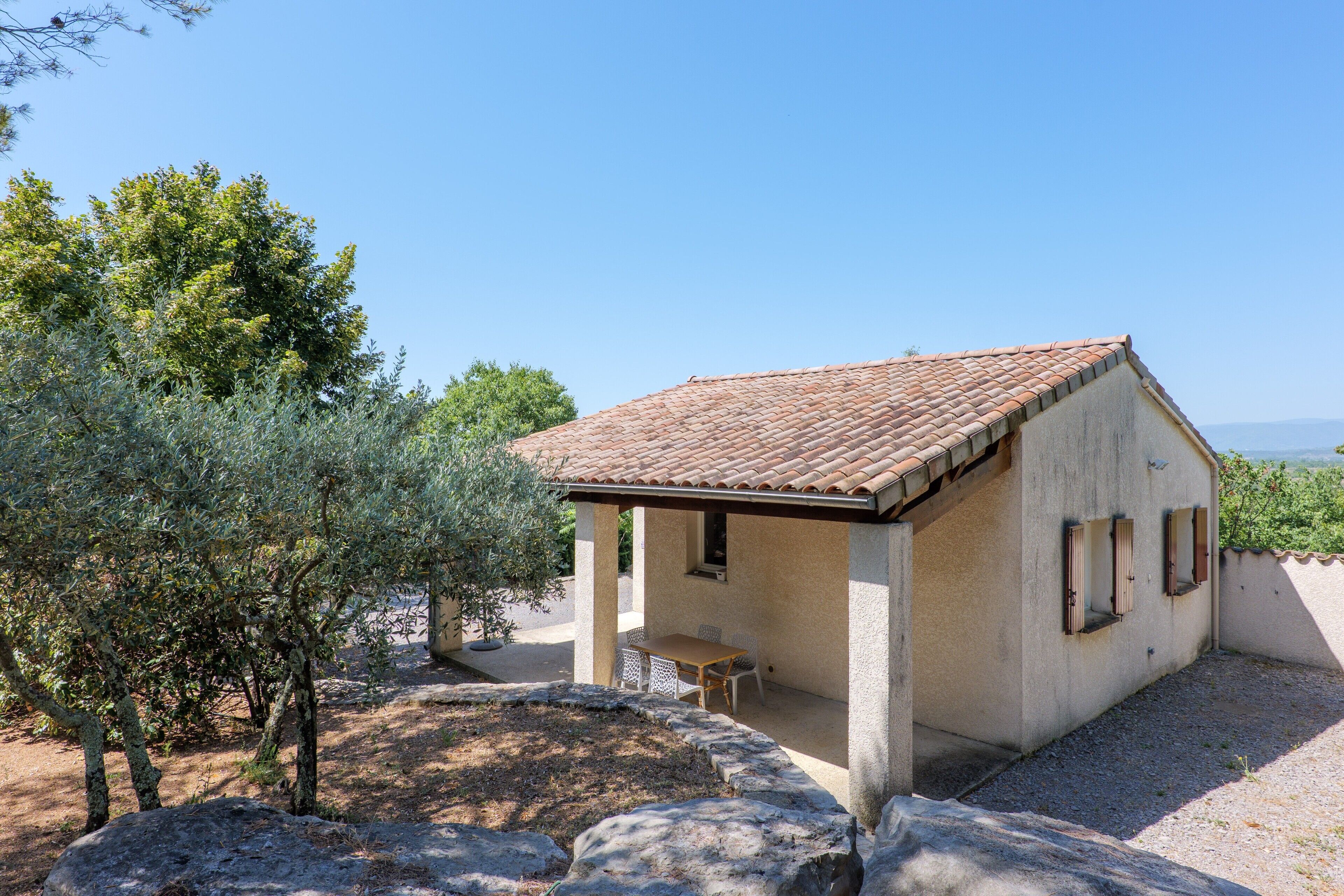 A small building with a tiled roof, a covered patio, and a view of the landscape.