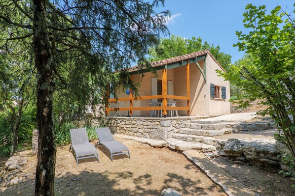 Une maison en pierre dotée d’un balcon, de deux fauteuils et d’un mur en pierre.