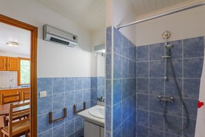 Une salle de bain avec des carreaux bleus, une douche, un lavabo et une chaise en bois.