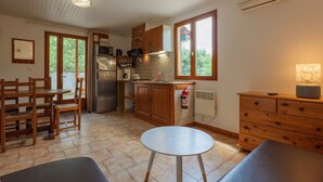 Une cuisine dotée de meubles en bois, d’un réfrigérateur, d’un four à micro-ondes et d’un coin repas avec des chaises et une table.