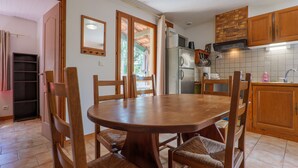 Un coin repas avec une table et des chaises en bois, une cuisine avec des meubles en bois et un dosseret carrelé.