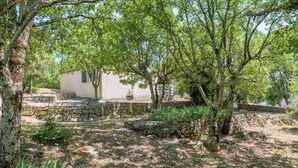 Un bâtiment aux murs de pierre, à l’extérieur blanc, entouré d’arbres et de verdure.