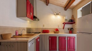 Une cuisine avec un plan de travail en bois, un évier, un grille-pain rouge et un réfrigérateur.