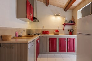 Een keuken met een houten aanrecht, een spoelbak, een rode toaster en een koelkast.