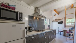 Une cuisine moderne équipée d’un four à micro-ondes, d’une cuisinière et d’une machine à café. On y trouve également un coin repas avec une table et des chaises, ainsi qu’un escalier menant à une mezzanine.