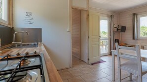 A kitchen with a stove, sink, and wooden walls. - Gîte Romarin 1 – Village Holiday Rentals (Joyeuse)