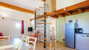 Eine Küche mit einer Wendeltreppe, einem Esstisch mit Stühlen, einem Kühlschrank und einer Mikrowelle.