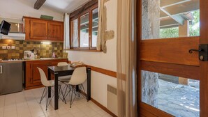 Une cuisine avec des meubles en bois, une table à manger avec des chaises, un four à micro-ondes encastré et une fenêtre donnant sur l’extérieur.