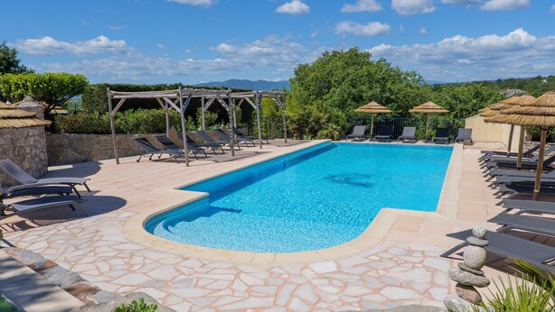 Une piscine avec des chaises longues, une pergola et une terrasse dallée de pierres.