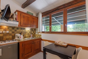 A kitchen with wooden cabinets, a gas stove, a coffee maker, and a window with blinds.