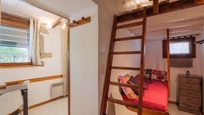 Une chambre avec un lit en mezzanine, une échelle en bois, un bureau et une commode.
