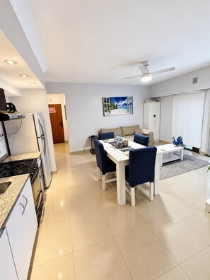 A modern kitchen with a stove, refrigerator, and dining area with a table and chairs.