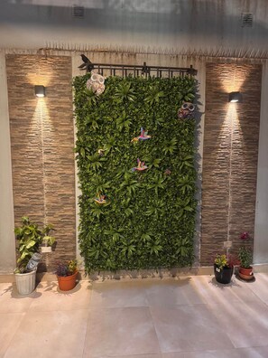 A wall with a vertical garden, decorative bird figures, and two wall-mounted lights.