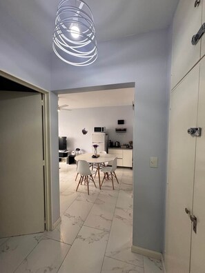 A modern kitchen with white cabinets, a dining area with a round table and chairs, and a unique ceiling light fixture.