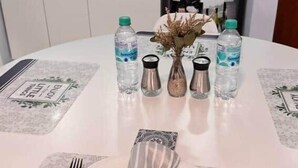 Una mesa de comedor dispuesta con platos, cubiertos, botellas de agua y saleros y pimenteros.