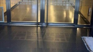 Un vestíbulo de hotel con un separador de vidrio, una escalera y el número '635' en la pared.