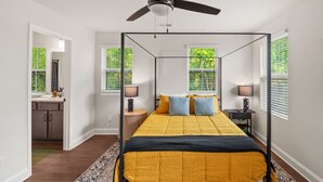 Ein Schlafzimmer mit Himmelbett, zwei Nachttischlampen und Deckenventilator.