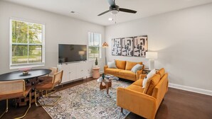 Ein modernes Wohnzimmer mit Fernseher, Sofa und Couchtisch.