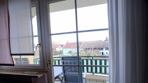 A balcony with a view of houses, a chair, and a radiator.