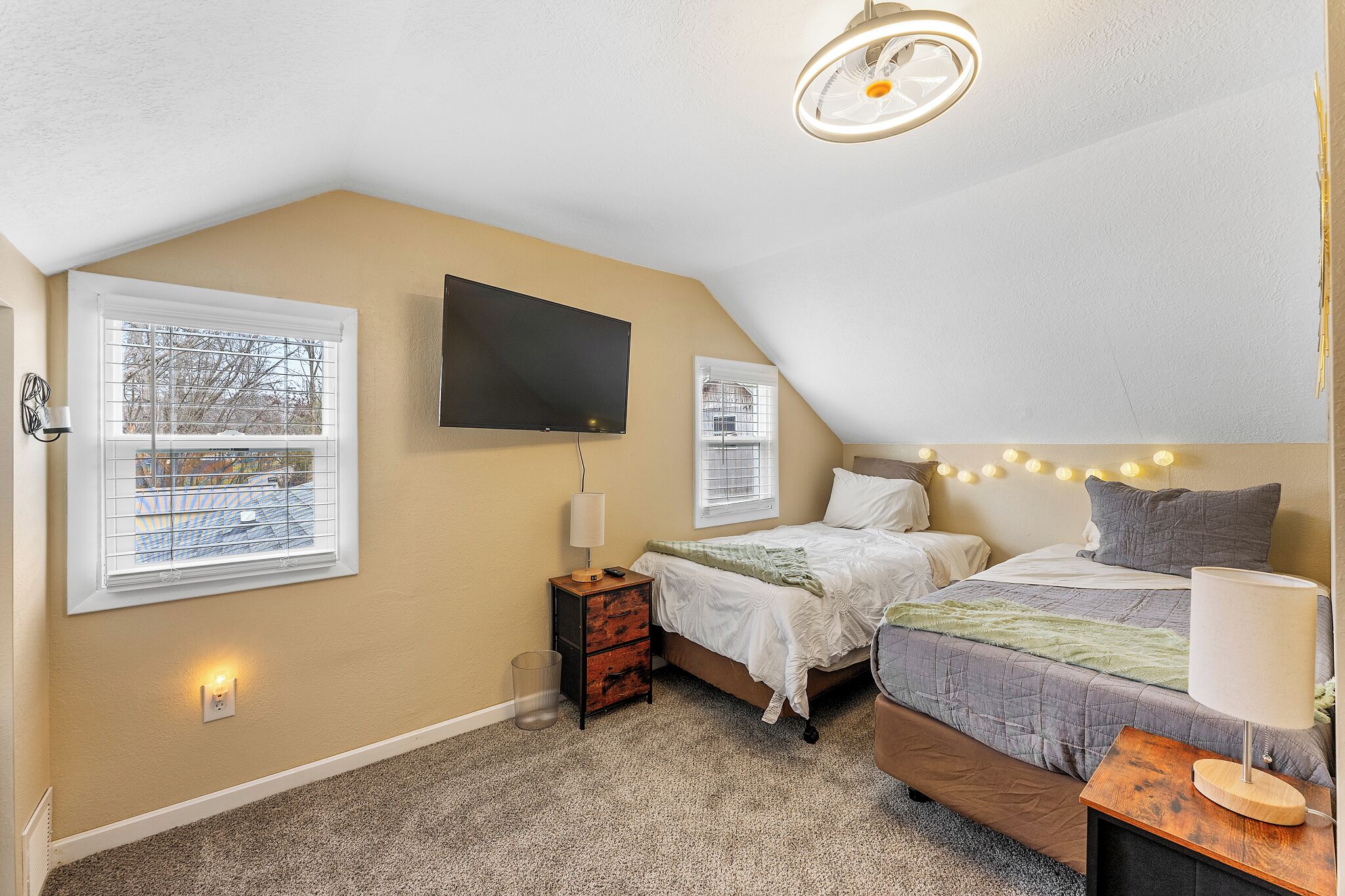 A bedroom with two beds, a TV, a lamp, and a ceiling fan.