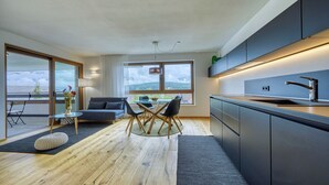 A modern kitchen with dark cabinetry and a stainless steel sink. - Apartment with a view of the surrounding mountains (Pfalzen)