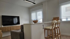 Eine moderne Küche mit integriertem Fernseher, Holzhockern und einem großen Fenster.