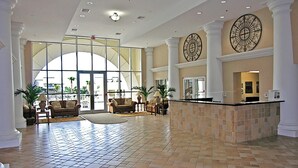 A spacious lobby with a high ceiling, large windows, and a reception desk. - Ariel Dunes II 1305 (Miramar Beach)