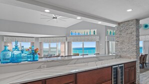 A spacious kitchen with a large island, stone accent wall, and a view of the ocean. - Cabana Club C408- Sugar Sand Shores (Destin)