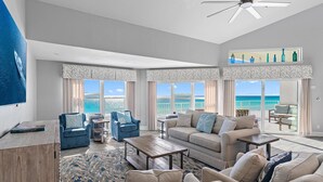A spacious living room with a large window overlooking the beach, a ceiling fan, and a coffee table. - Cabana Club C408- Sugar Sand Shores (Destin)