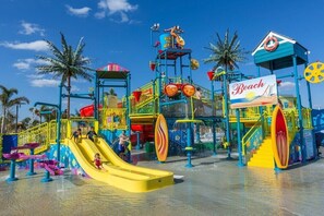 A water park with slides, a lifebuoy sign, and palm trees. - Spacious 5-bedroom home with private pool, AC, & Waterpark in charming Kissimmee (Kissimmee)