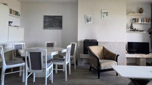A modern living room with a dining area, a TV, and a fireplace. - 2 Person Apartment With sea View (De Koog)