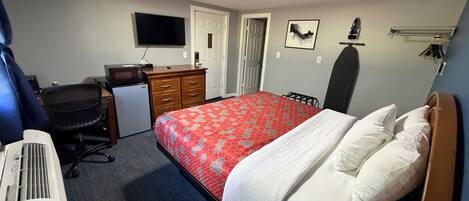Quarto de hotel com cama, escrivaninha, cadeira, televisão e aquecedor.